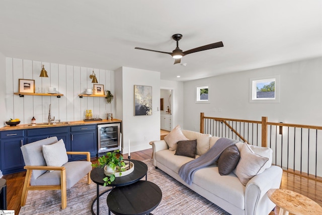 living room with light wood-type flooring, indoor wet bar, wine cooler, and ceiling fan