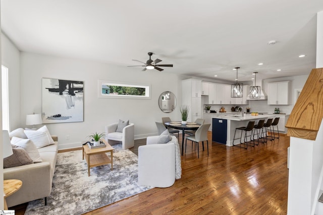 living room featuring ceiling fan, sink, and dark hardwood / wood-style flooring