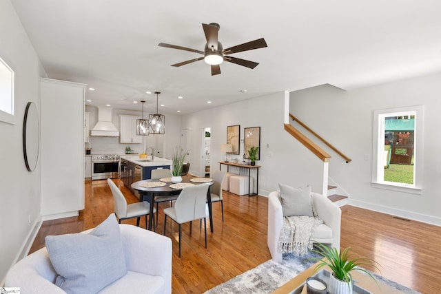 dining room featuring ceiling fan with notable chandelier, light hardwood / wood-style floors, and sink