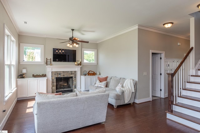 living room with a tiled fireplace, dark wood-type flooring, and a wealth of natural light