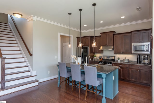 kitchen featuring an island with sink, dark stone countertops, sink, dark hardwood / wood-style flooring, and appliances with stainless steel finishes