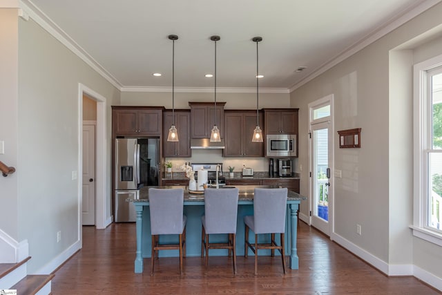 kitchen featuring an island with sink, hanging light fixtures, stainless steel appliances, dark hardwood / wood-style floors, and a kitchen bar