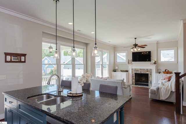 kitchen with dark stone counters, hanging light fixtures, dark wood-type flooring, and a healthy amount of sunlight