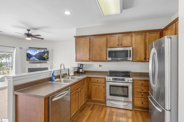 kitchen featuring light hardwood / wood-style flooring, stainless steel appliances, sink, kitchen peninsula, and ceiling fan