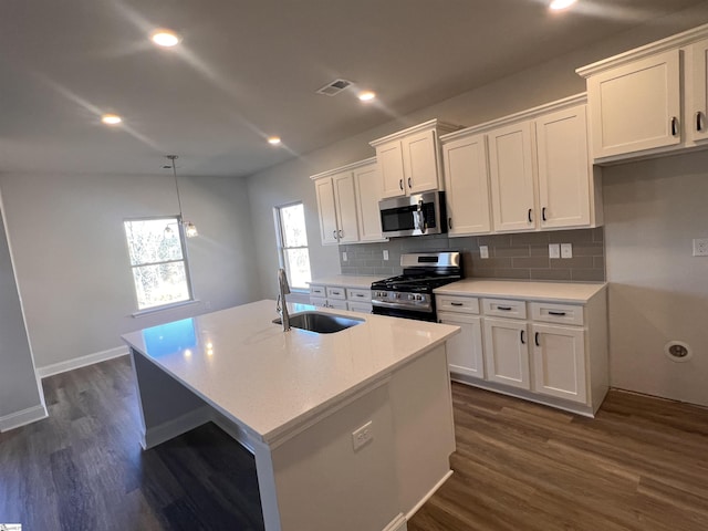 kitchen with appliances with stainless steel finishes, a sink, dark wood finished floors, and white cabinets