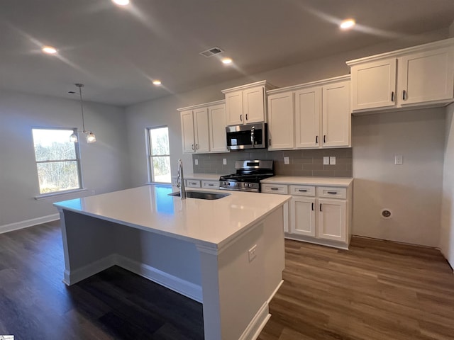 kitchen with a center island with sink, stainless steel appliances, visible vents, white cabinetry, and a sink