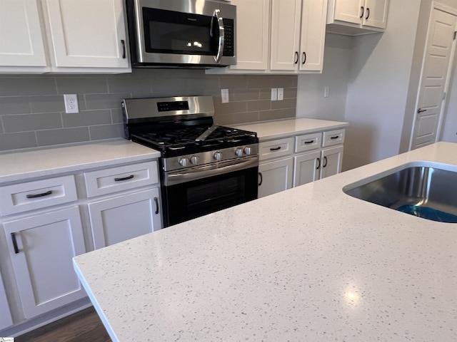 kitchen with stainless steel appliances, white cabinets, and tasteful backsplash