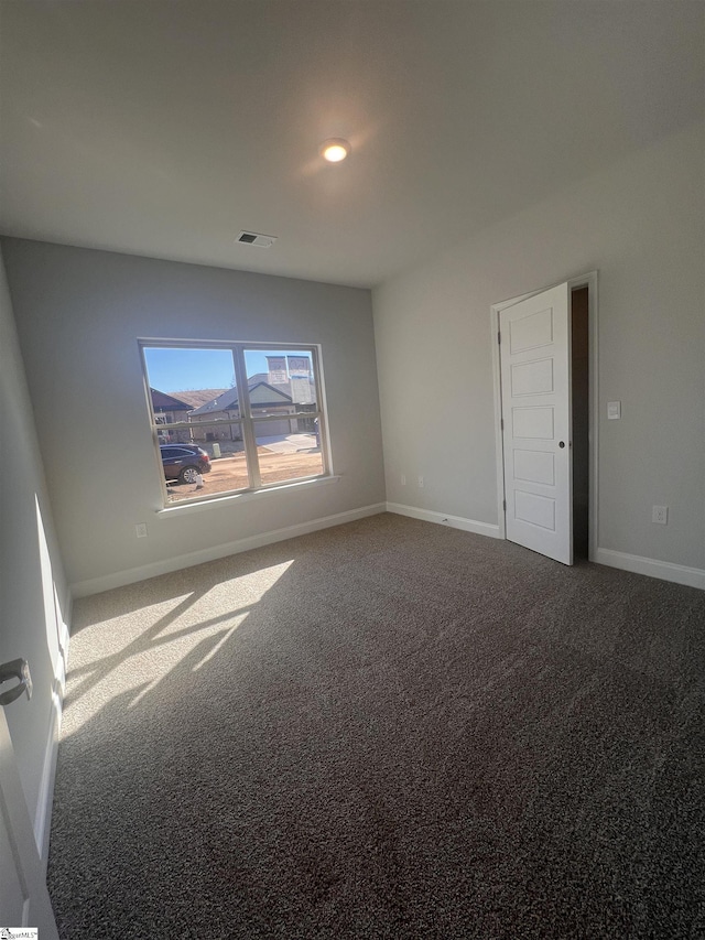 carpeted spare room featuring baseboards and visible vents