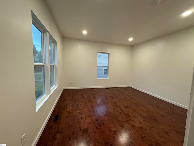 spare room with dark hardwood / wood-style flooring and plenty of natural light