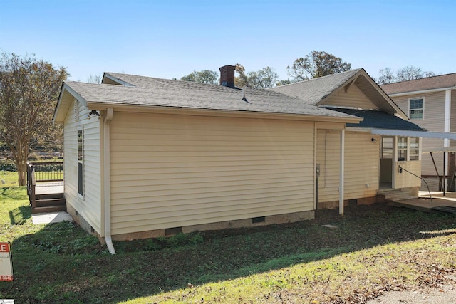 view of side of home with roof with shingles, a yard, crawl space, and a chimney