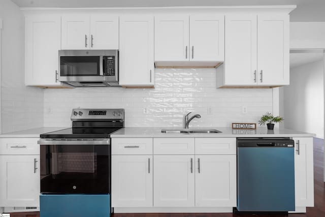 kitchen featuring stainless steel appliances, light countertops, a sink, and decorative backsplash