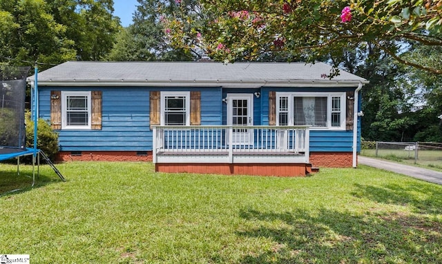 ranch-style home featuring a front lawn, a trampoline, and a deck