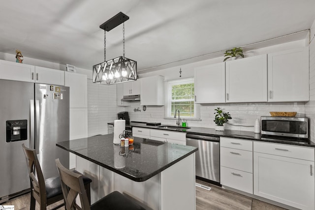 kitchen featuring appliances with stainless steel finishes, sink, white cabinets, and a kitchen breakfast bar