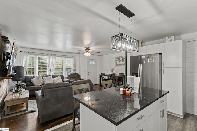 kitchen with white cabinetry, a kitchen bar, a kitchen island, ceiling fan, and stainless steel refrigerator with ice dispenser