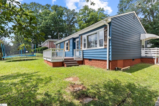 view of front of home with a deck, a front lawn, and a trampoline