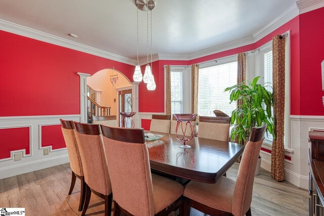 dining room with ornate columns, crown molding, and light hardwood / wood-style flooring