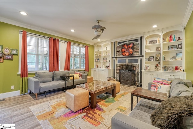 living room featuring light wood-type flooring, crown molding, and a stone fireplace