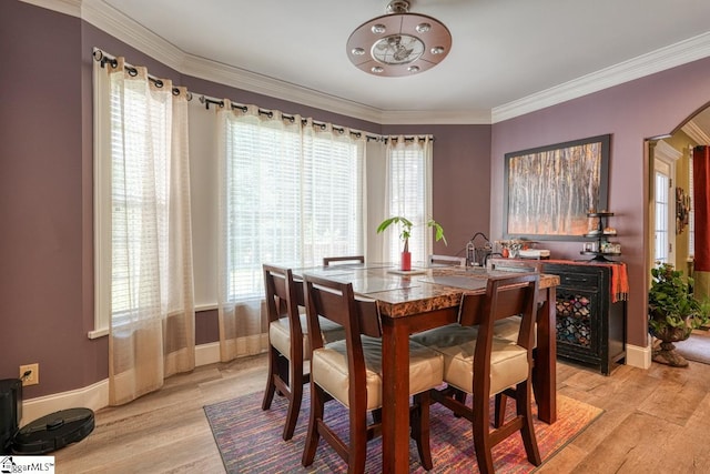 dining space featuring ornamental molding and light hardwood / wood-style floors