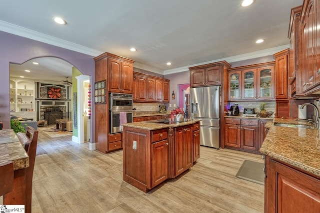 kitchen featuring a fireplace, light hardwood / wood-style flooring, sink, a center island, and appliances with stainless steel finishes