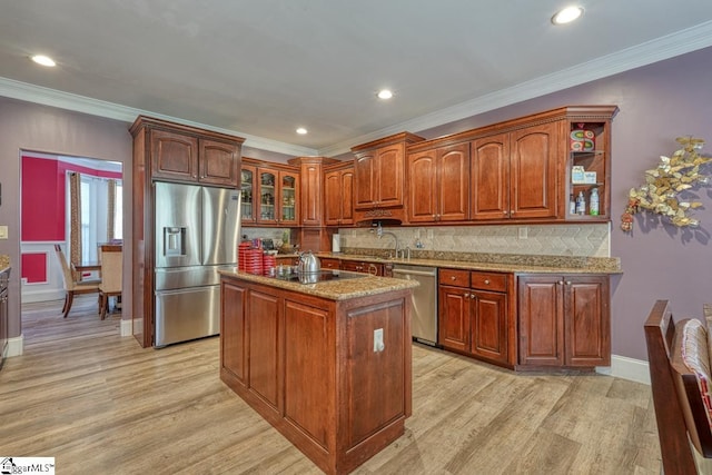 kitchen with appliances with stainless steel finishes, light stone counters, a center island, and light hardwood / wood-style flooring