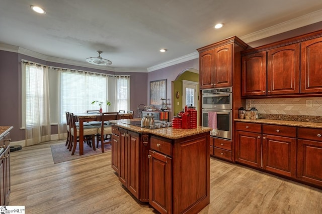 kitchen with a wealth of natural light, a kitchen island, light wood-type flooring, and double oven