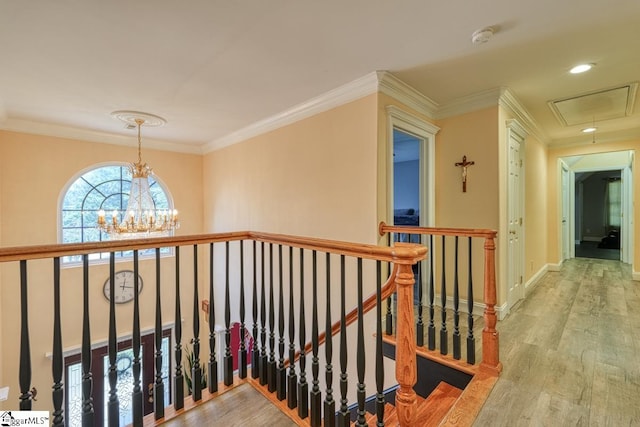 hall with ornamental molding, wood-type flooring, and an inviting chandelier