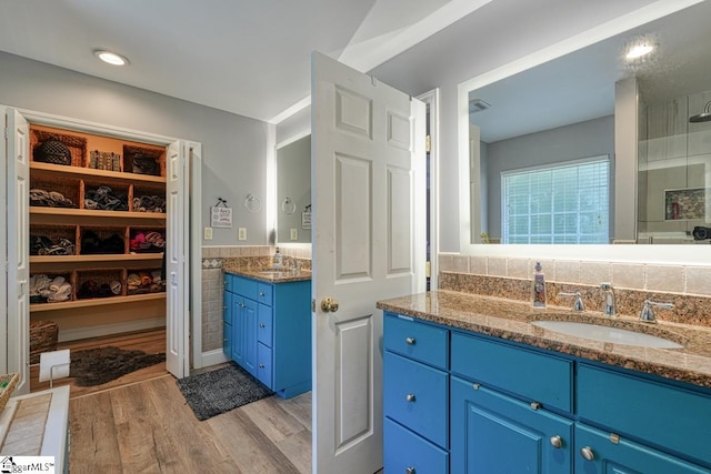 bathroom featuring backsplash, wood-type flooring, walk in shower, and vanity