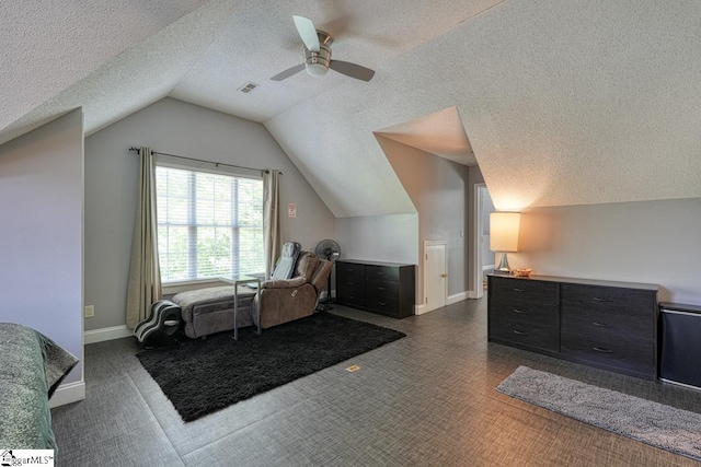 interior space featuring lofted ceiling, ceiling fan, dark carpet, and a textured ceiling