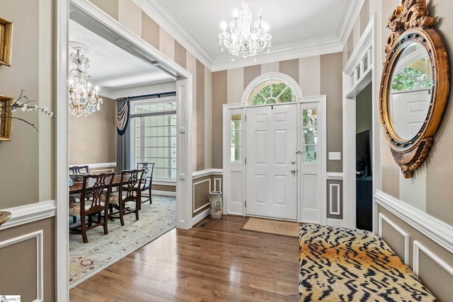 foyer entrance featuring ornamental molding, wood-type flooring, plenty of natural light, and an inviting chandelier