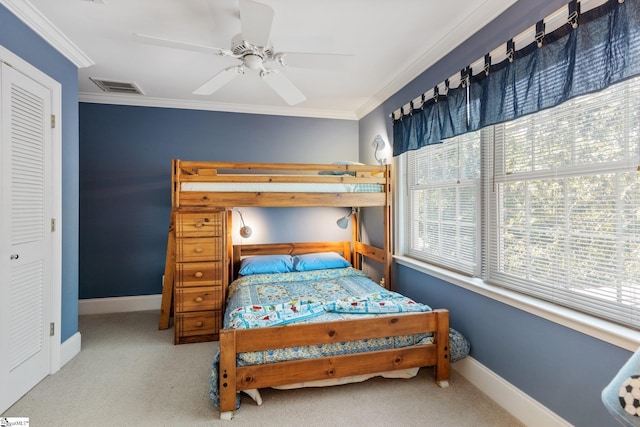 carpeted bedroom with ornamental molding, a closet, and ceiling fan