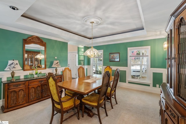 carpeted dining room with a raised ceiling, an inviting chandelier, and ornamental molding