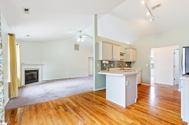 kitchen featuring a peninsula, a sink, visible vents, open floor plan, and light countertops