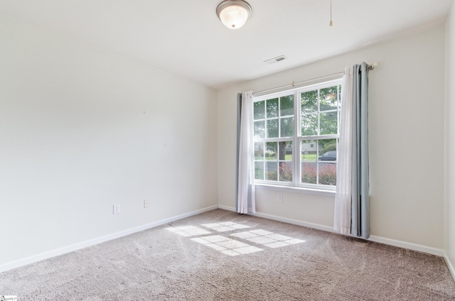 spare room with baseboards, visible vents, and light colored carpet