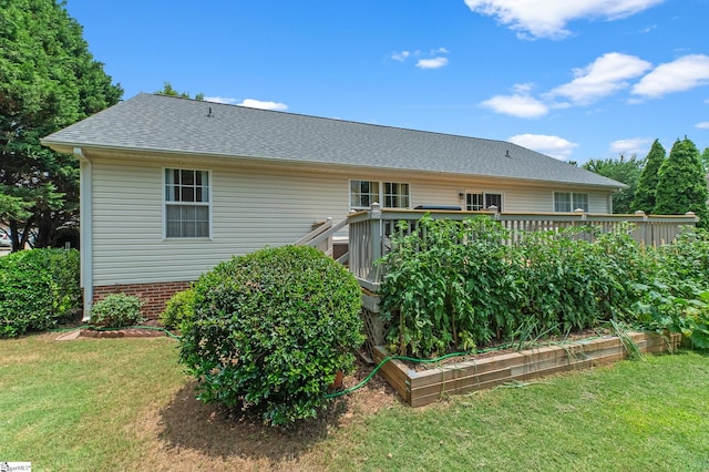 back of property featuring roof with shingles, a lawn, and a deck