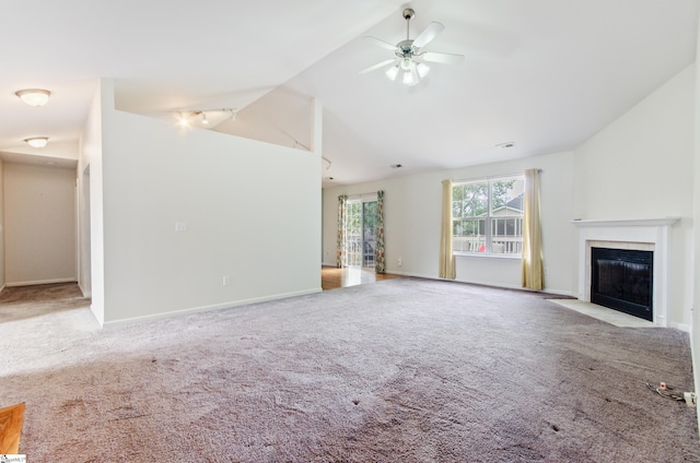 unfurnished living room with vaulted ceiling, ceiling fan, a fireplace with flush hearth, and light colored carpet