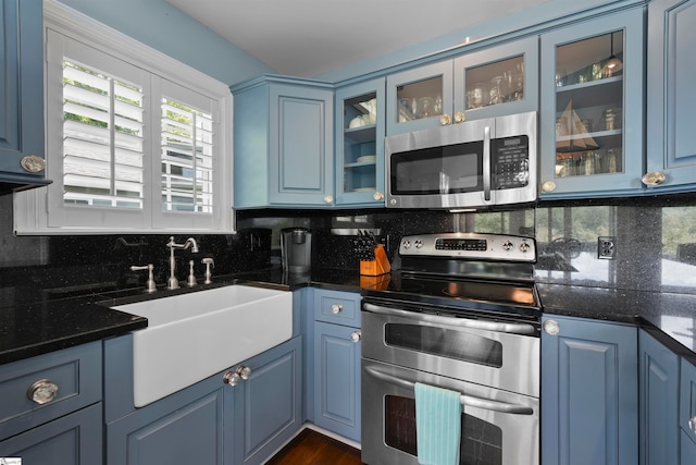 kitchen featuring appliances with stainless steel finishes, blue cabinets, tasteful backsplash, and sink