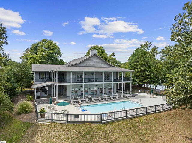 rear view of property featuring a community pool and a patio