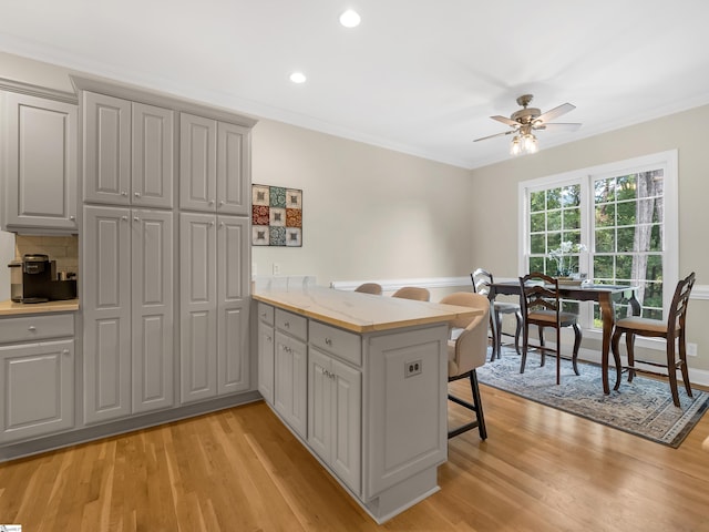 kitchen featuring light wood-type flooring, gray cabinetry, kitchen peninsula, and ceiling fan