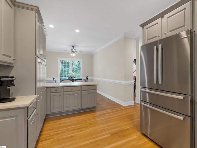 kitchen featuring light hardwood / wood-style flooring, crown molding, stainless steel refrigerator, gray cabinets, and ceiling fan