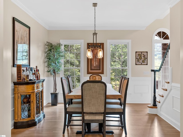 dining space with hardwood / wood-style flooring, a notable chandelier, and ornamental molding