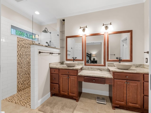 bathroom featuring ornamental molding, vanity, a tile shower, and tile patterned floors