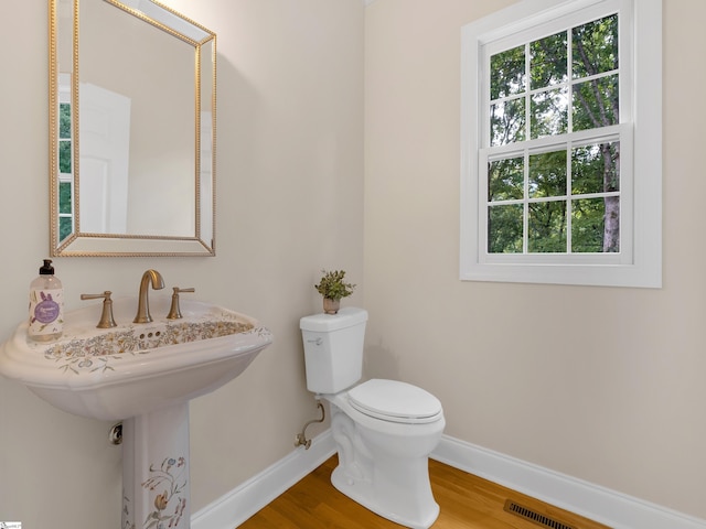 bathroom with hardwood / wood-style floors, toilet, and a healthy amount of sunlight