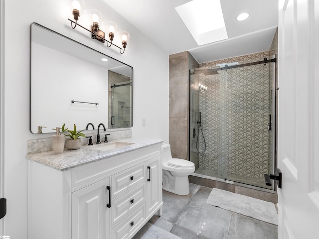 bathroom with a shower with shower door, toilet, a skylight, and vanity