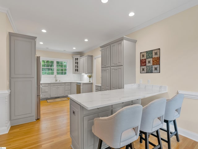 kitchen with a breakfast bar area, gray cabinetry, and kitchen peninsula