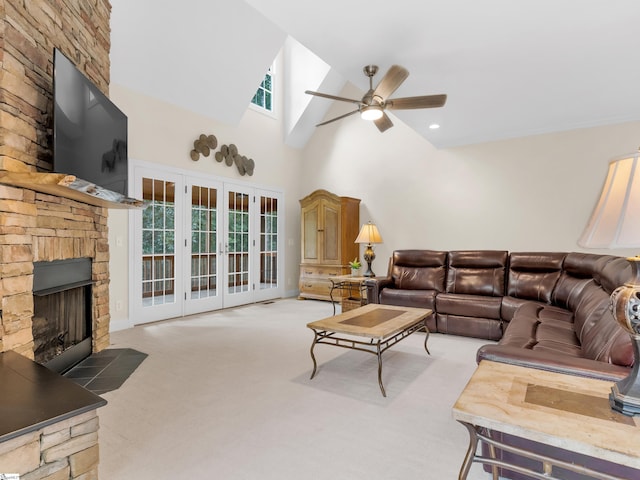 living room featuring ceiling fan, a stone fireplace, high vaulted ceiling, and light carpet