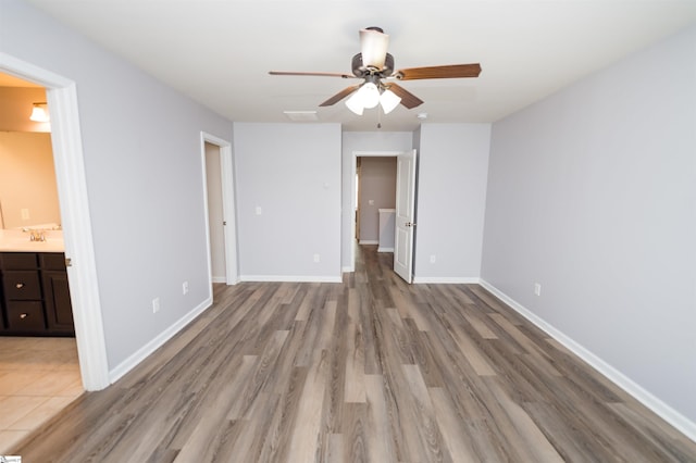 unfurnished bedroom with visible vents, baseboards, ensuite bathroom, wood finished floors, and a sink