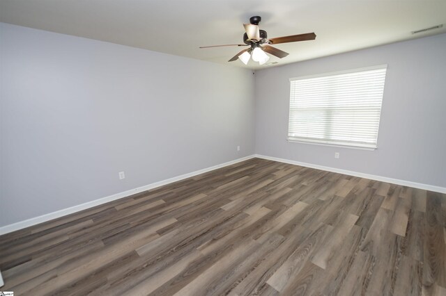 unfurnished room featuring dark wood-style floors, visible vents, a ceiling fan, and baseboards