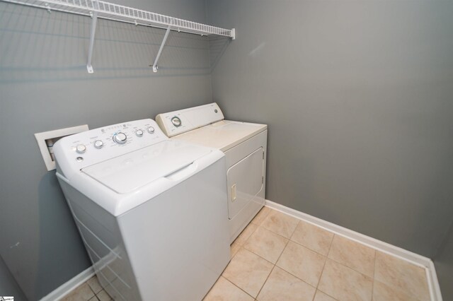 laundry area with washer and dryer, laundry area, light tile patterned flooring, and baseboards