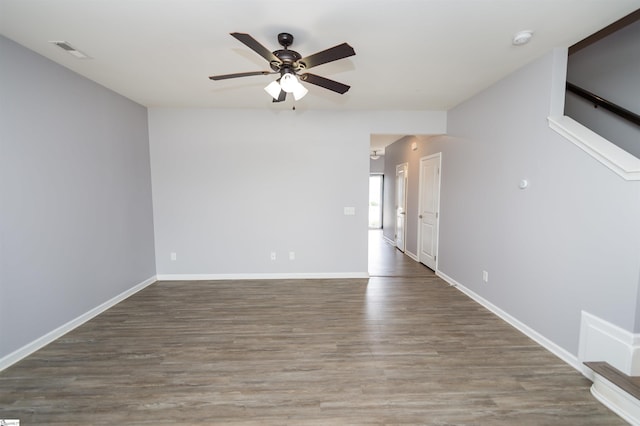 empty room with visible vents, a ceiling fan, baseboards, and wood finished floors