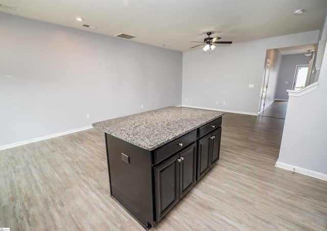kitchen with visible vents, a kitchen island, open floor plan, light wood-style floors, and baseboards